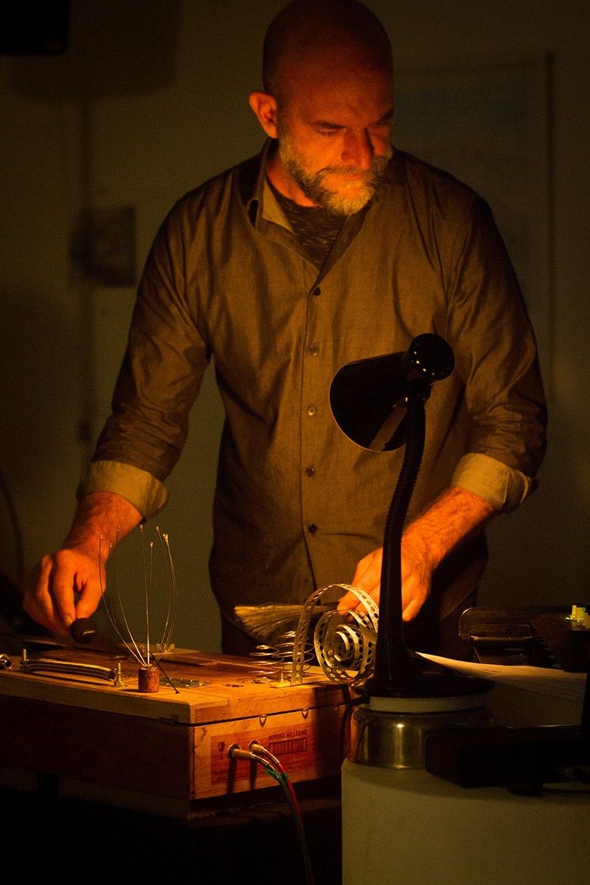 Fabio tocando uma noisebox à luz de uma luminária.